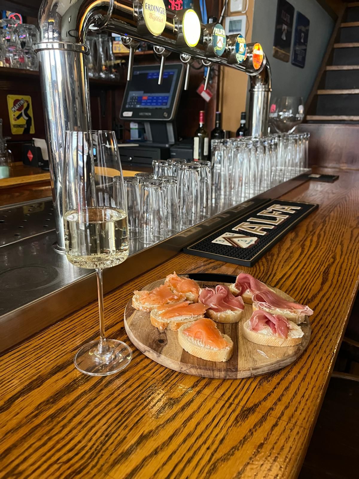Glas witte wijn met een plankje bijpassende hapjes aan de bar van Cafe Salud Groningen